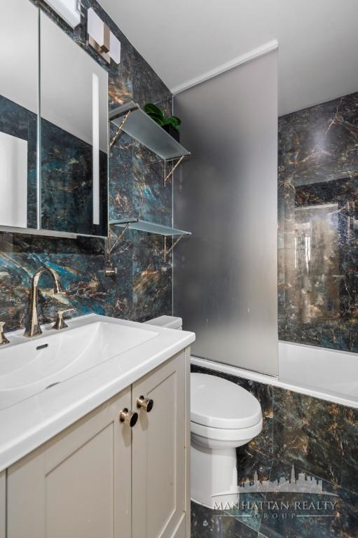 full bathroom with vanity, toilet, backsplash, and shower / tub combination