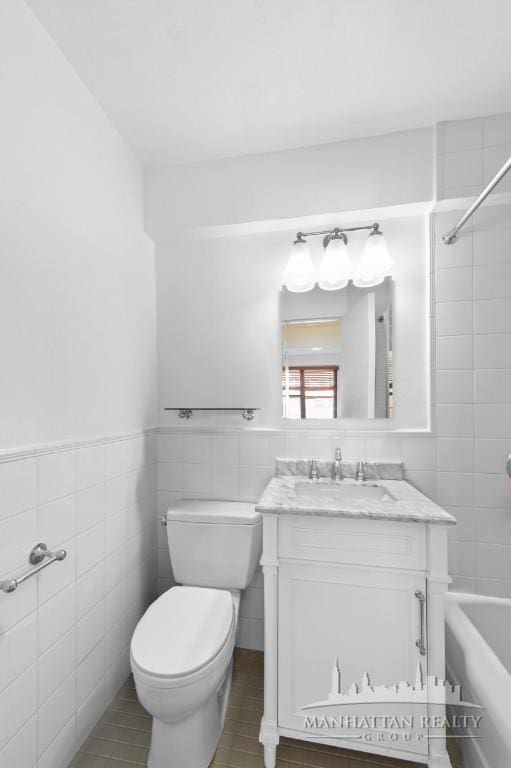 bathroom with tile patterned floors, shower / bath combination, vanity, toilet, and tile walls