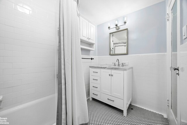 155 E 49th St Unit 1A, New York City, NY 10017 - full bath featuring vanity, tile walls, shower / tub combo with curtain, a wainscoted wall, and tile patterned floors
