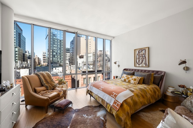 bedroom with a skyline view, wood finished floors, and multiple windows