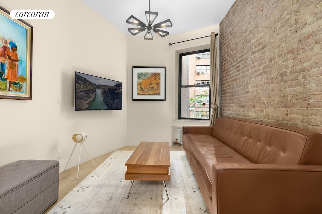 living room with brick wall, wood finished floors, and visible vents