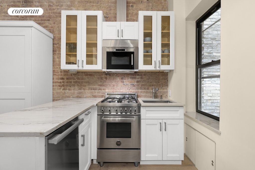 kitchen with a sink, appliances with stainless steel finishes, decorative backsplash, and white cabinets