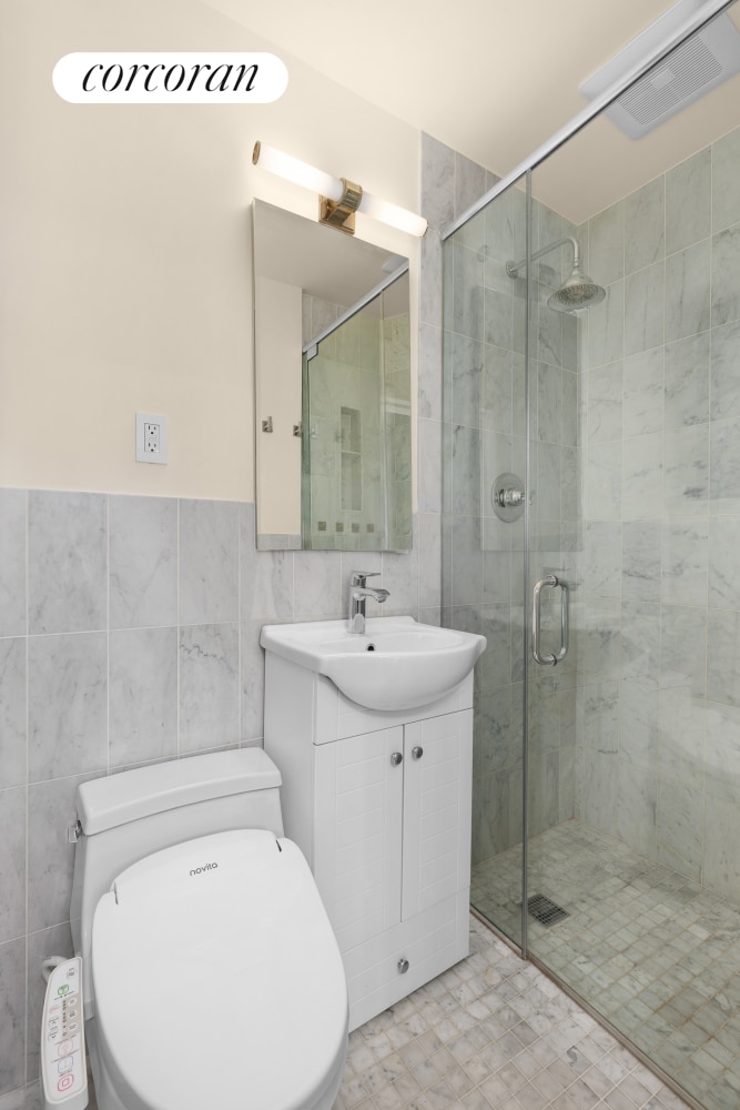 full bath featuring visible vents, tile walls, a shower stall, vanity, and toilet