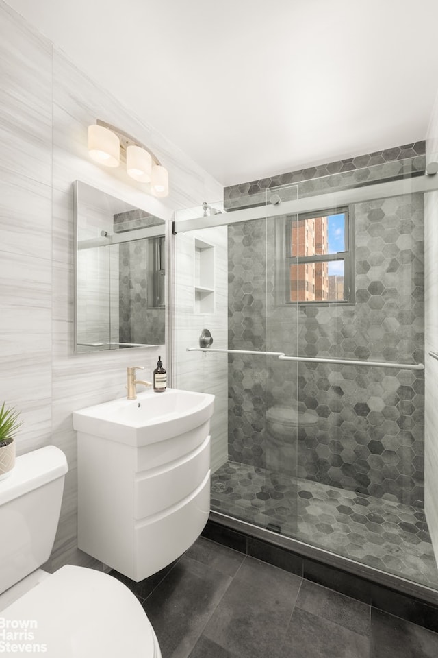 bathroom featuring a shower stall, vanity, tile walls, toilet, and tile patterned flooring