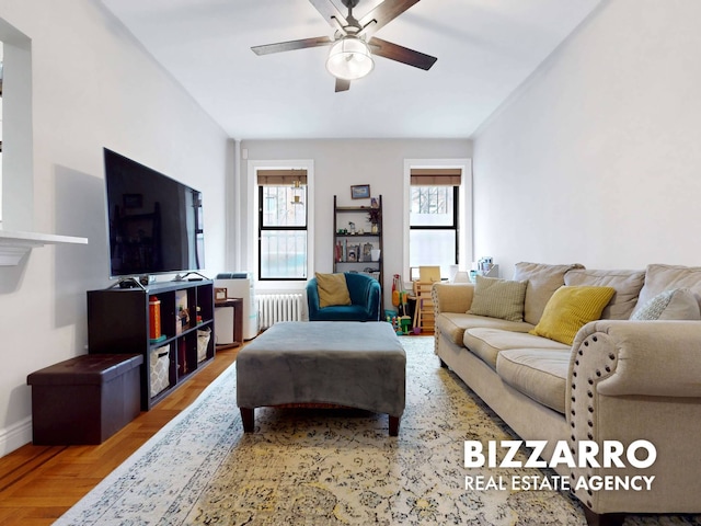 living area with ceiling fan, baseboards, radiator heating unit, and a healthy amount of sunlight