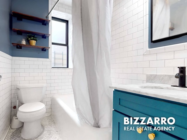 bathroom featuring tile patterned floors, toilet, vanity, tile walls, and shower / bath combo with shower curtain