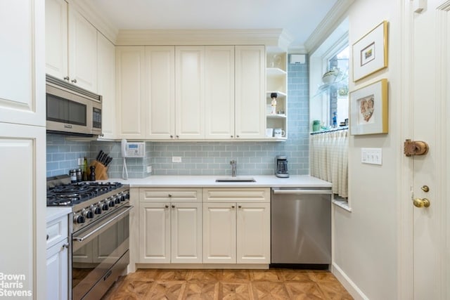 kitchen featuring white cabinetry, light countertops, a sink, stainless steel appliances, and backsplash