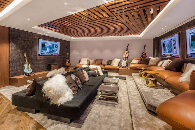 cinema with a tray ceiling, an accent wall, and wood finished floors