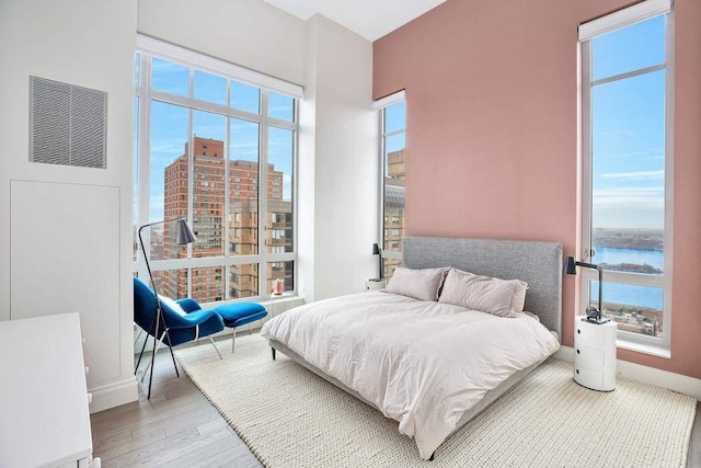 bedroom with a water view, baseboards, and wood finished floors