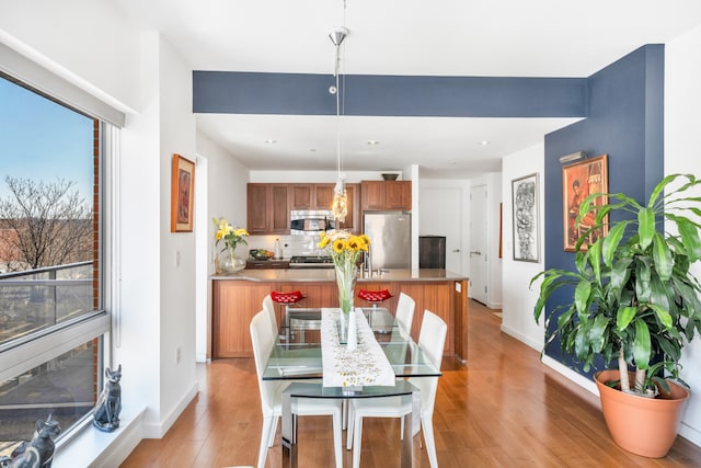 dining space with a wealth of natural light, light wood-style flooring, and baseboards