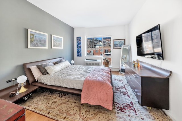 bedroom with light wood-style floors and an AC wall unit