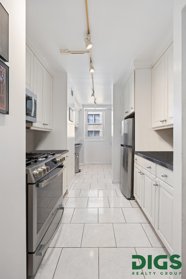 kitchen featuring appliances with stainless steel finishes, dark countertops, light tile patterned floors, baseboards, and white cabinetry