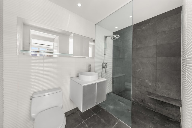 bathroom with tile walls, a walk in shower, toilet, and vanity