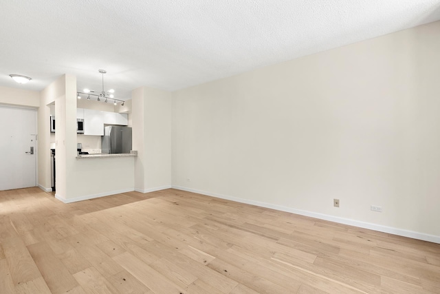 unfurnished living room featuring an inviting chandelier, baseboards, and light wood-style flooring