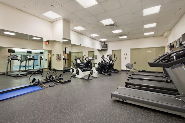 exercise room with visible vents, a drop ceiling, and a towering ceiling