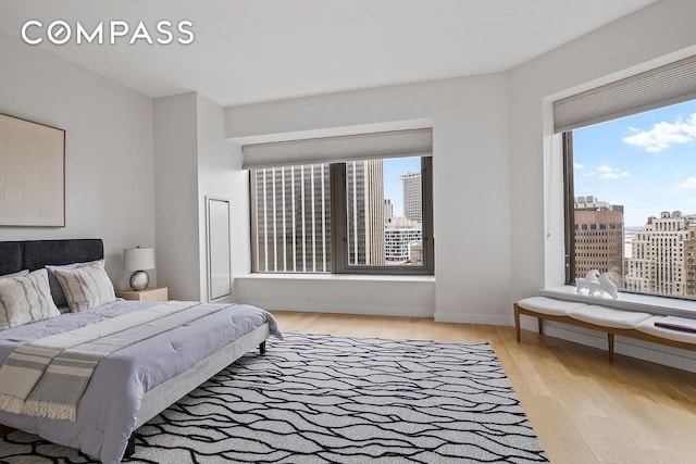 75 Wall St Unit 36F, New York City, NY 10005 - bedroom with a city view, multiple windows, and light wood-style flooring