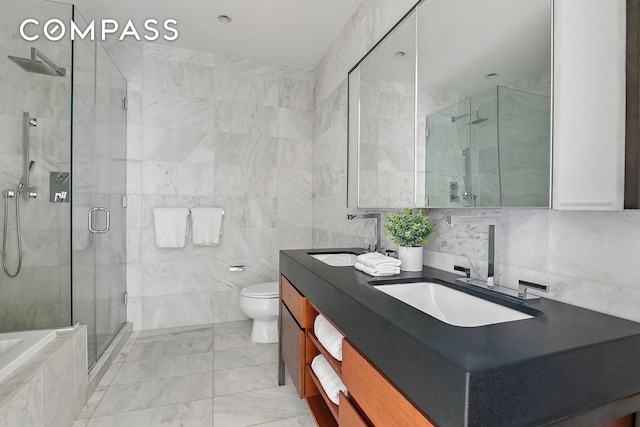 75 Wall St Unit 36F, New York City, NY 10005 - full bath featuring double vanity, a shower stall, tile walls, a relaxing tiled tub, and marble finish floors