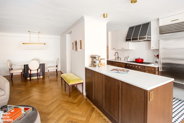 310 E 70th St Unit 4Lm, New York City, NY 10021 - kitchen featuring built in fridge, wall chimney range hood, cooktop, light countertops, and a sink