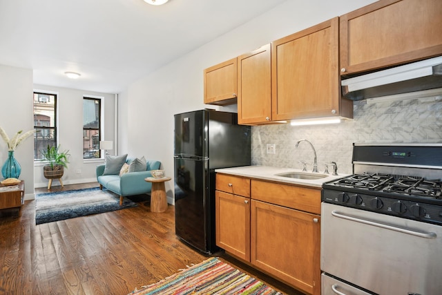 kitchen featuring a sink, freestanding refrigerator, backsplash, under cabinet range hood, and gas stove