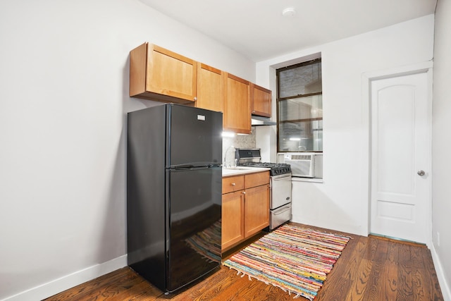 kitchen featuring freestanding refrigerator, under cabinet range hood, dark wood-style floors, and gas range oven