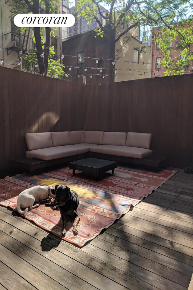 wooden terrace with an outdoor hangout area and fence