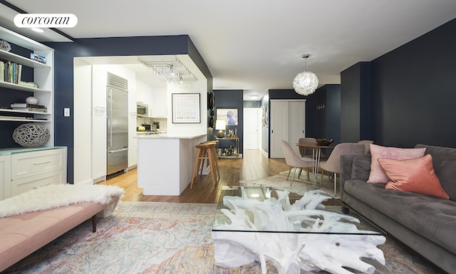 living area featuring visible vents, a notable chandelier, and light wood finished floors