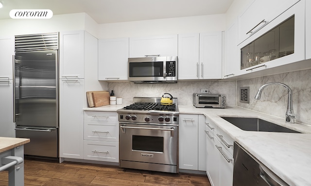 kitchen featuring a sink, a toaster, white cabinets, and high quality appliances