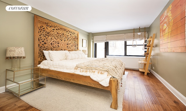 bedroom with baseboards, wood finished floors, and radiator