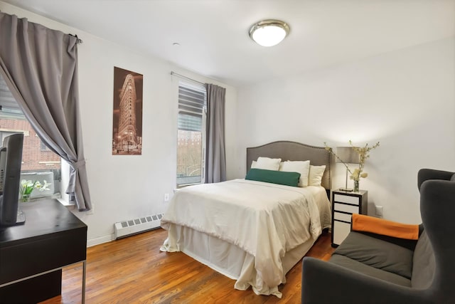 167 W 129th St Unit 4D, New York City, NY 10027 - bedroom featuring a baseboard radiator, wood finished floors, and baseboards
