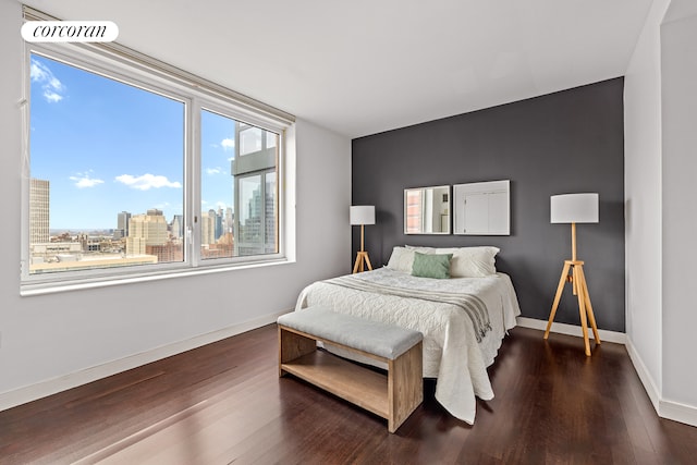 bedroom with a view of city, baseboards, visible vents, and wood finished floors