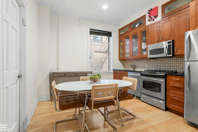 229 W 97th St Unit 6E, New York City, NY 10025 - kitchen featuring brown cabinets, backsplash, appliances with stainless steel finishes, and light wood-type flooring
