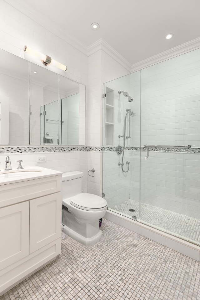 full bath with ornamental molding, a stall shower, toilet, vanity, and tile walls
