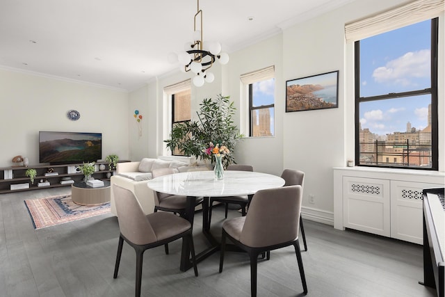 dining area featuring light wood-style flooring, a chandelier, crown molding, and baseboards