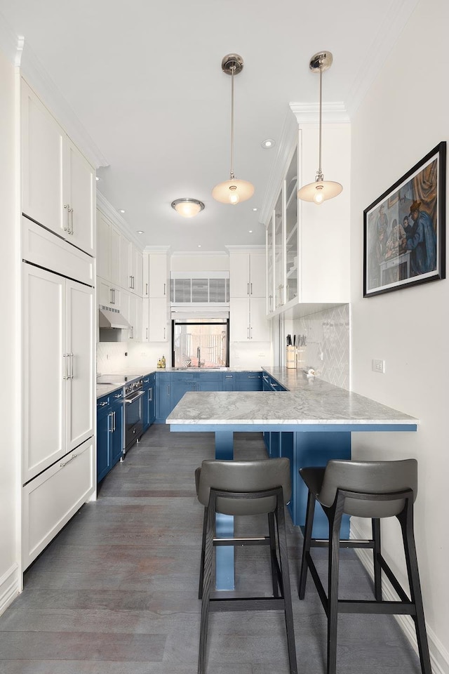 kitchen featuring blue cabinets, white cabinetry, a peninsula, under cabinet range hood, and stainless steel stove