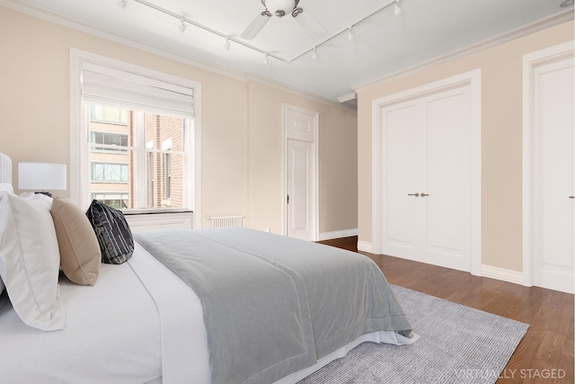 bedroom featuring track lighting, wood finished floors, ornamental molding, baseboards, and ceiling fan