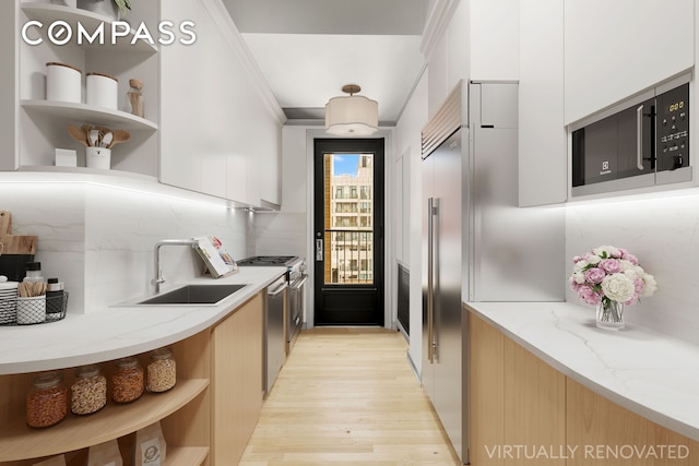 kitchen featuring open shelves, light wood-style floors, modern cabinets, a sink, and stainless steel appliances