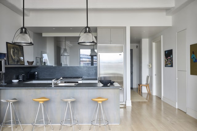 30 Main St Unit 7H, New York City, NY 11201 - kitchen with dark countertops, built in refrigerator, backsplash, light wood-style flooring, and a breakfast bar area