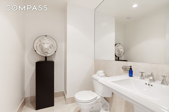 bathroom featuring toilet, baseboards, a sink, and tile patterned floors