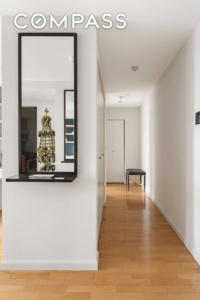 corridor with baseboards and light wood-type flooring