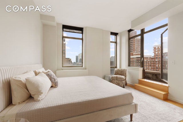 bedroom with a view of city, baseboards, and wood finished floors
