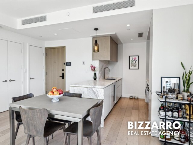 208 Delancey St Unit 8F, New York City, NY 10002 - kitchen with a sink, modern cabinets, light wood-type flooring, light stone countertops, and decorative light fixtures