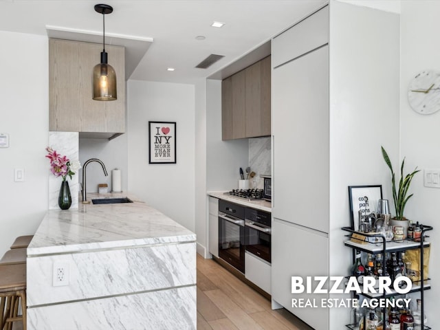 208 Delancey St Unit 8F, New York City, NY 10002 - kitchen with a sink, stainless steel appliances, modern cabinets, light wood-type flooring, and light stone countertops