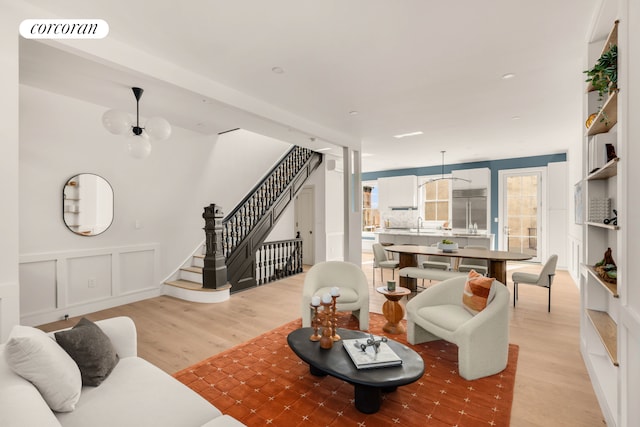 64 2nd St, New York City, NY 11231 - living room featuring stairs, light wood-style flooring, a wainscoted wall, and a decorative wall