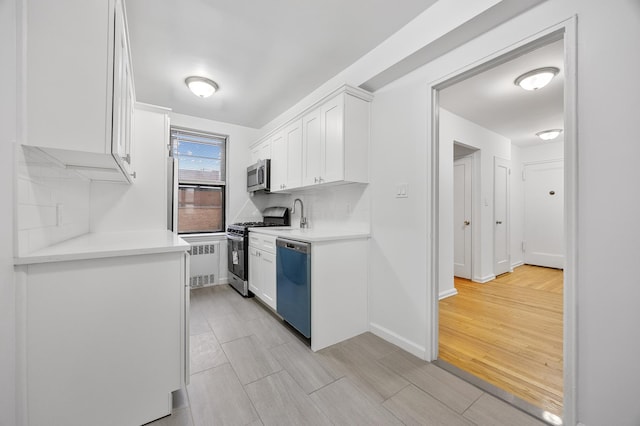 302 96th St Unit 2-W, New York City, NY 11209 - kitchen featuring stainless steel appliances, white cabinetry, light countertops, light wood-style flooring, and tasteful backsplash