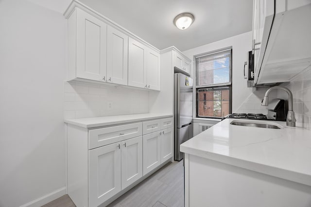 302 96th St Unit 2-W, New York City, NY 11209 - kitchen with stainless steel appliances, white cabinetry, tasteful backsplash, light stone counters, and a sink