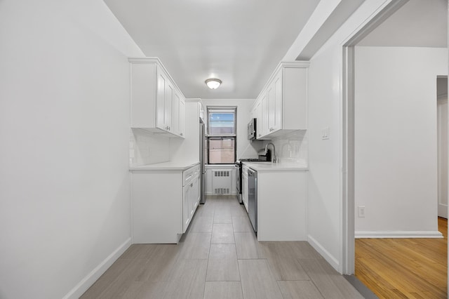 302 96th St Unit 2-W, New York City, NY 11209 - kitchen with stainless steel appliances, light countertops, white cabinetry, and light wood-type flooring