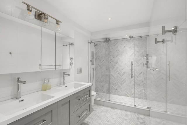 69 5th Ave Unit 9Gh, New York City, NY 10003 - bathroom featuring a shower stall, tile walls, double vanity, and toilet