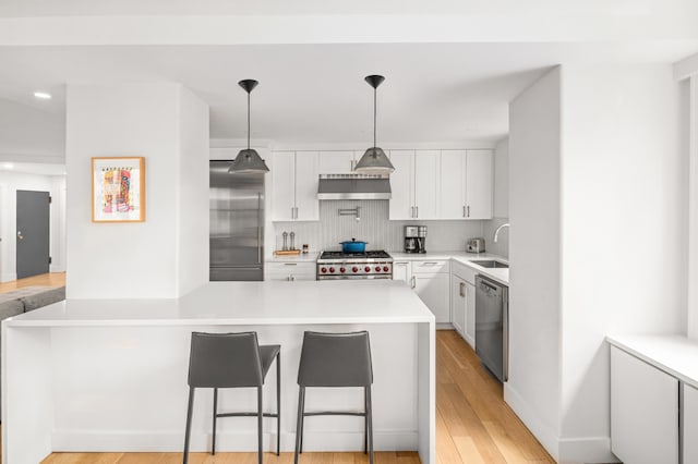69 5th Ave Unit 9Gh, New York City, NY 10003 - kitchen featuring appliances with stainless steel finishes, wall chimney range hood, a sink, tasteful backsplash, and light countertops
