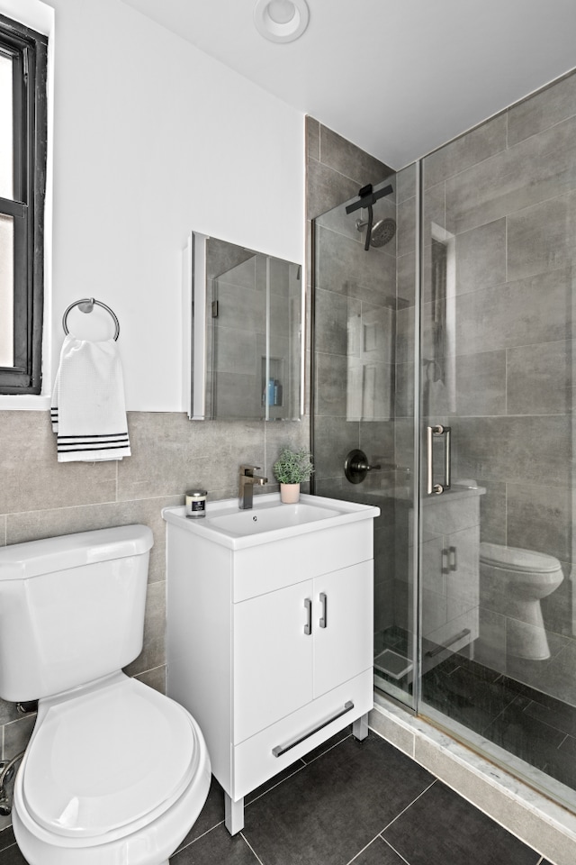 bathroom featuring tile patterned floors, toilet, a stall shower, and tile walls