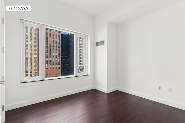 spare room featuring dark wood-style flooring and baseboards